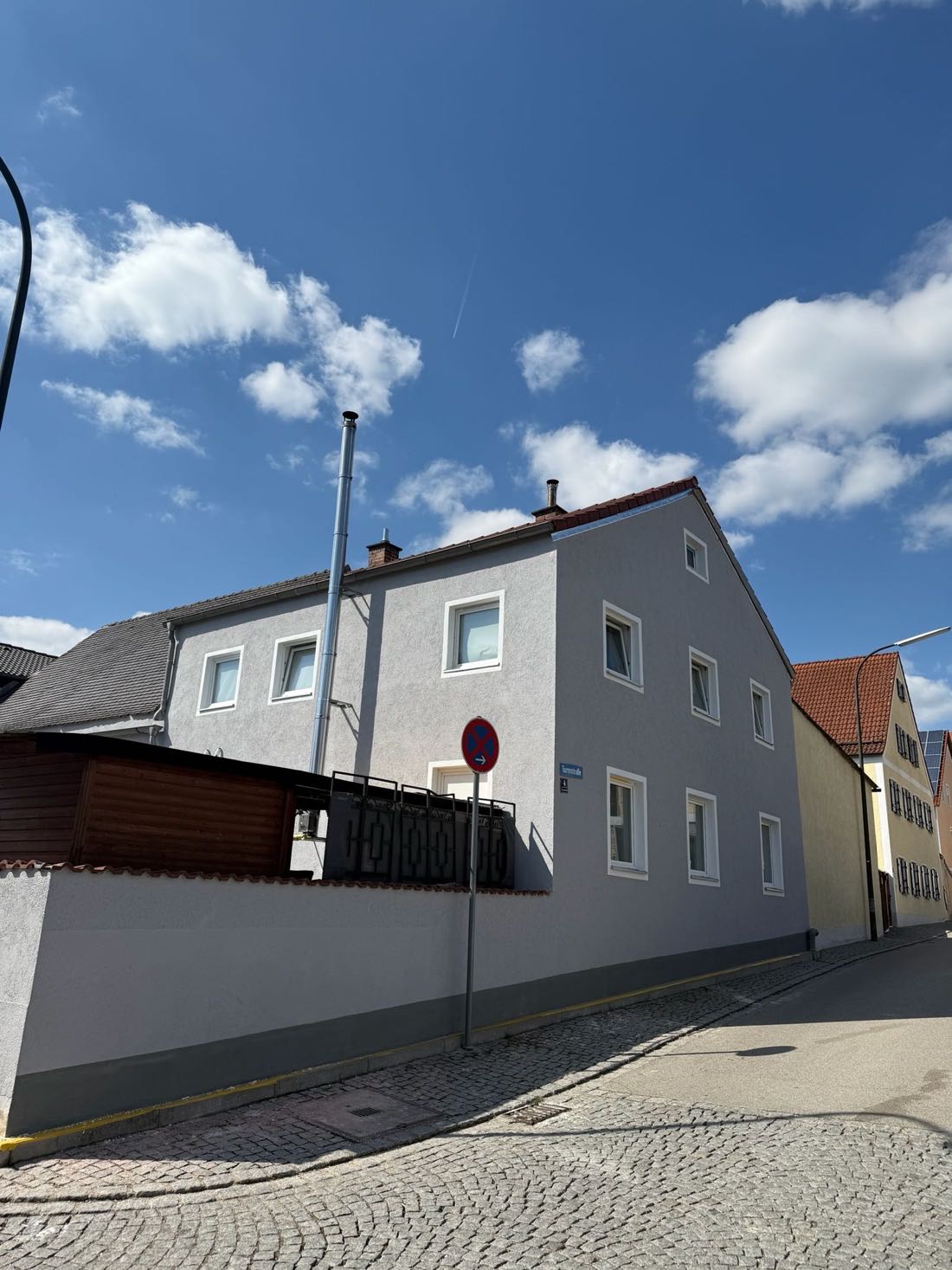 Altbaufassade in Hellgrau bei Sonnenschein mit blauem Himmel