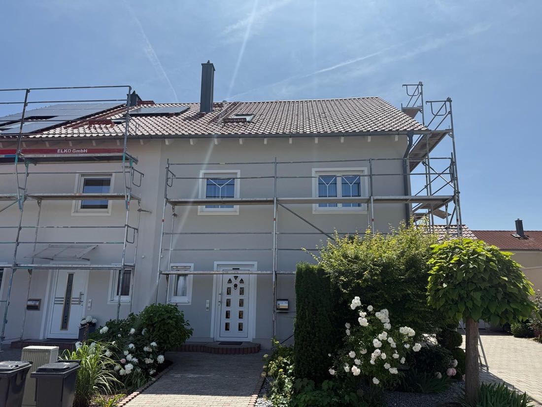 Doppelhaushälfte mit Gerüst während der Fassadenarbeiten bei Sonnenschein