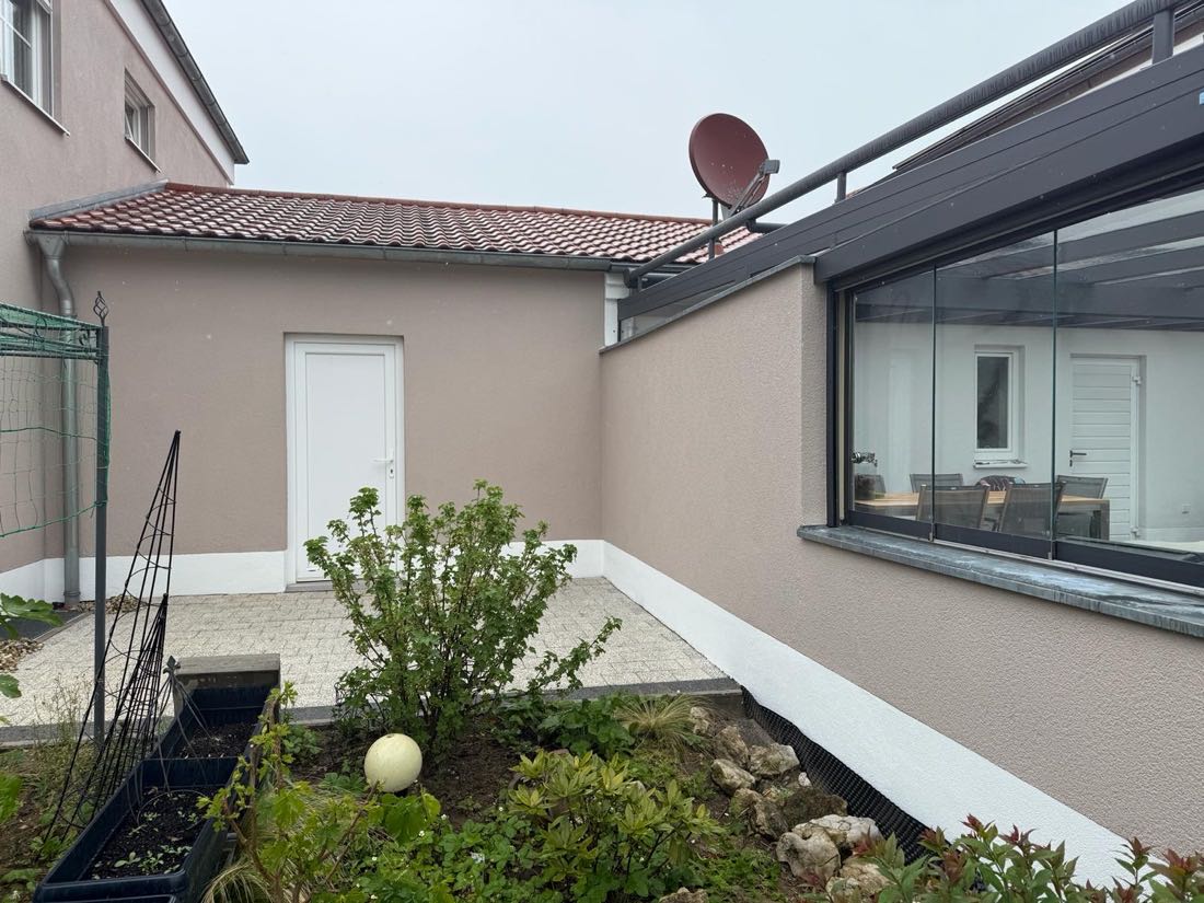 Innenhof mit neu gestrichener Fassade in Greige und weißem Sockel