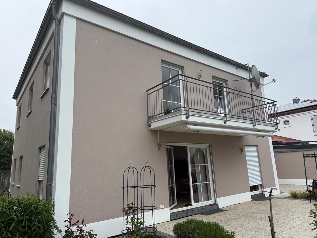 Hausansicht mit Balkon und Terrasse nach dem Fassadenanstrich in Greige