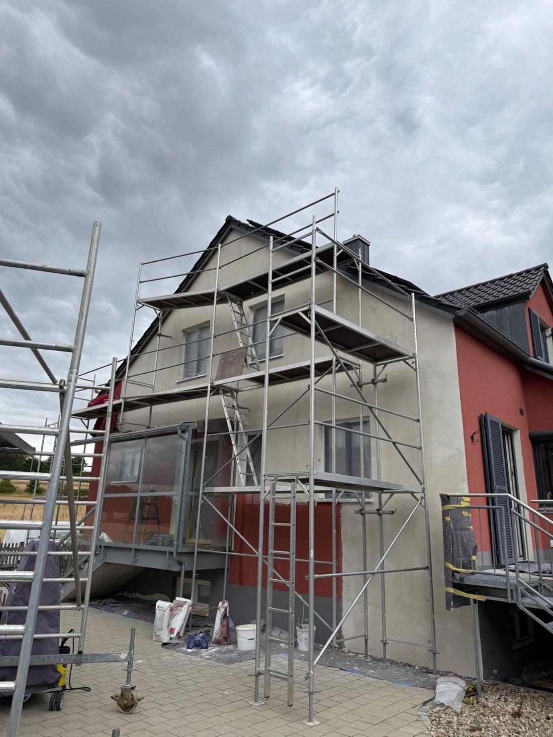 Hausseite mit neu aufgebautem Putz vor dem Anstrich, Gerüst steht noch