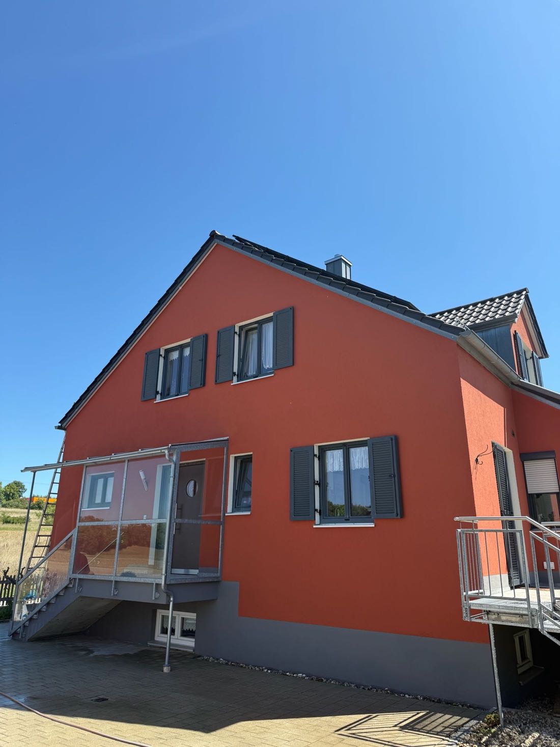 Giebelseite eines rot gestrichenen Hauses mit weißen Fenstern