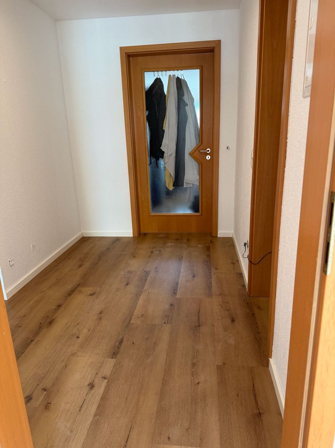 Flur mit neu verlegtem Boden in Eichenoptik und hell gestrichenen Wänden