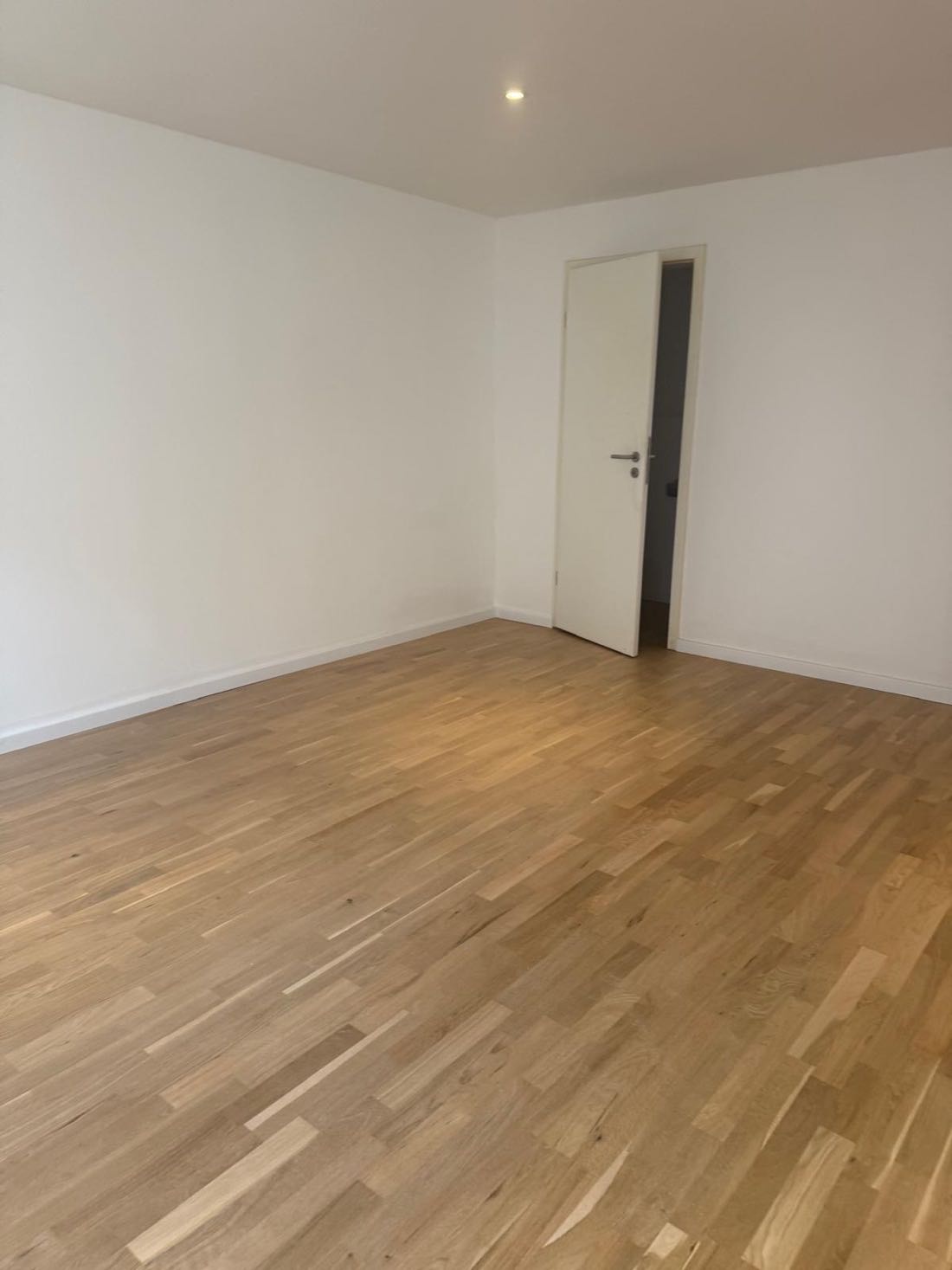 Fertig gestrichener Wohnraum mit weißen Wänden und Eichenparkett