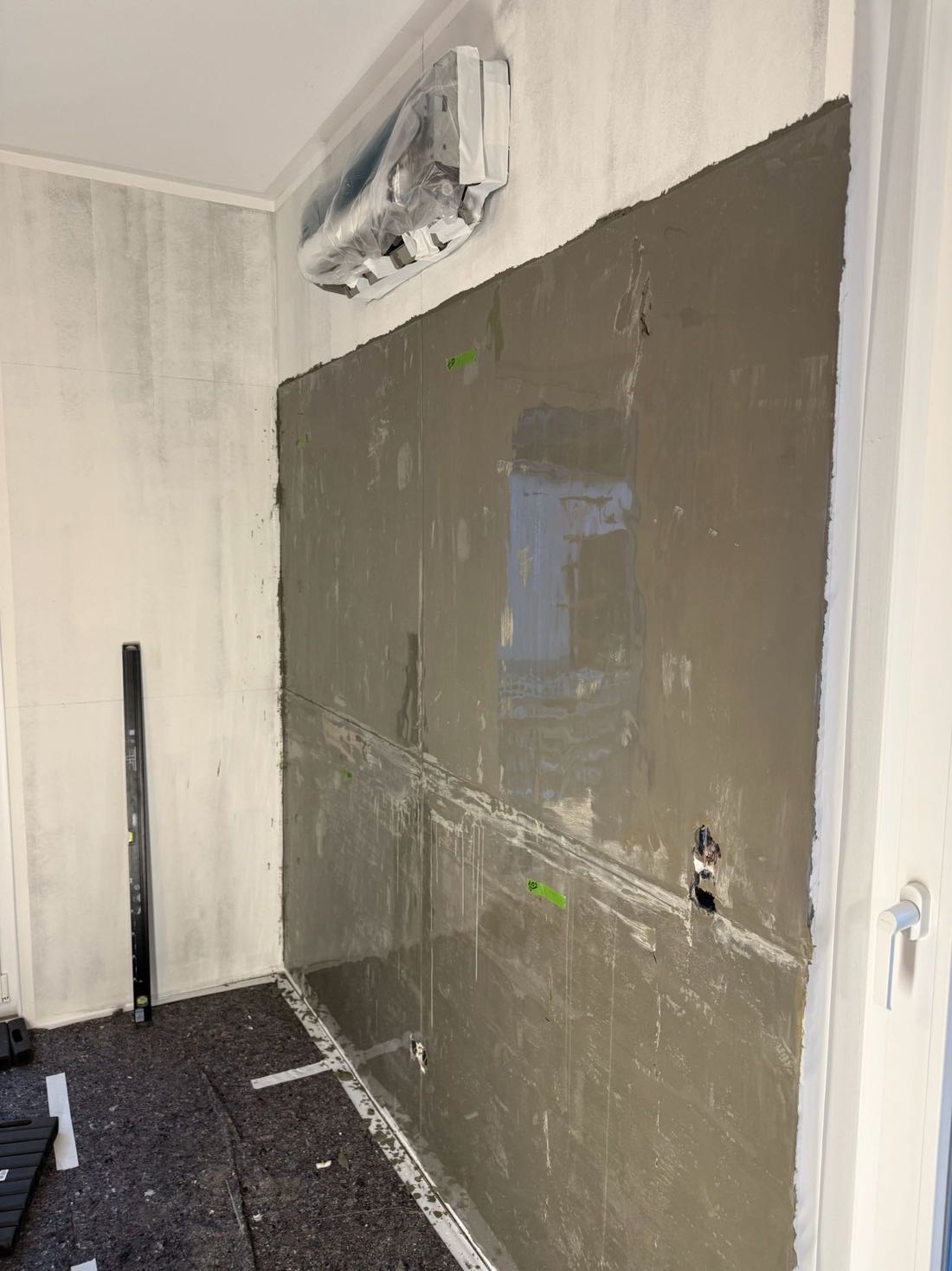 Wand während des Auftrags der Sichtbeton-Spachtelmasse, halb fertige Fläche
