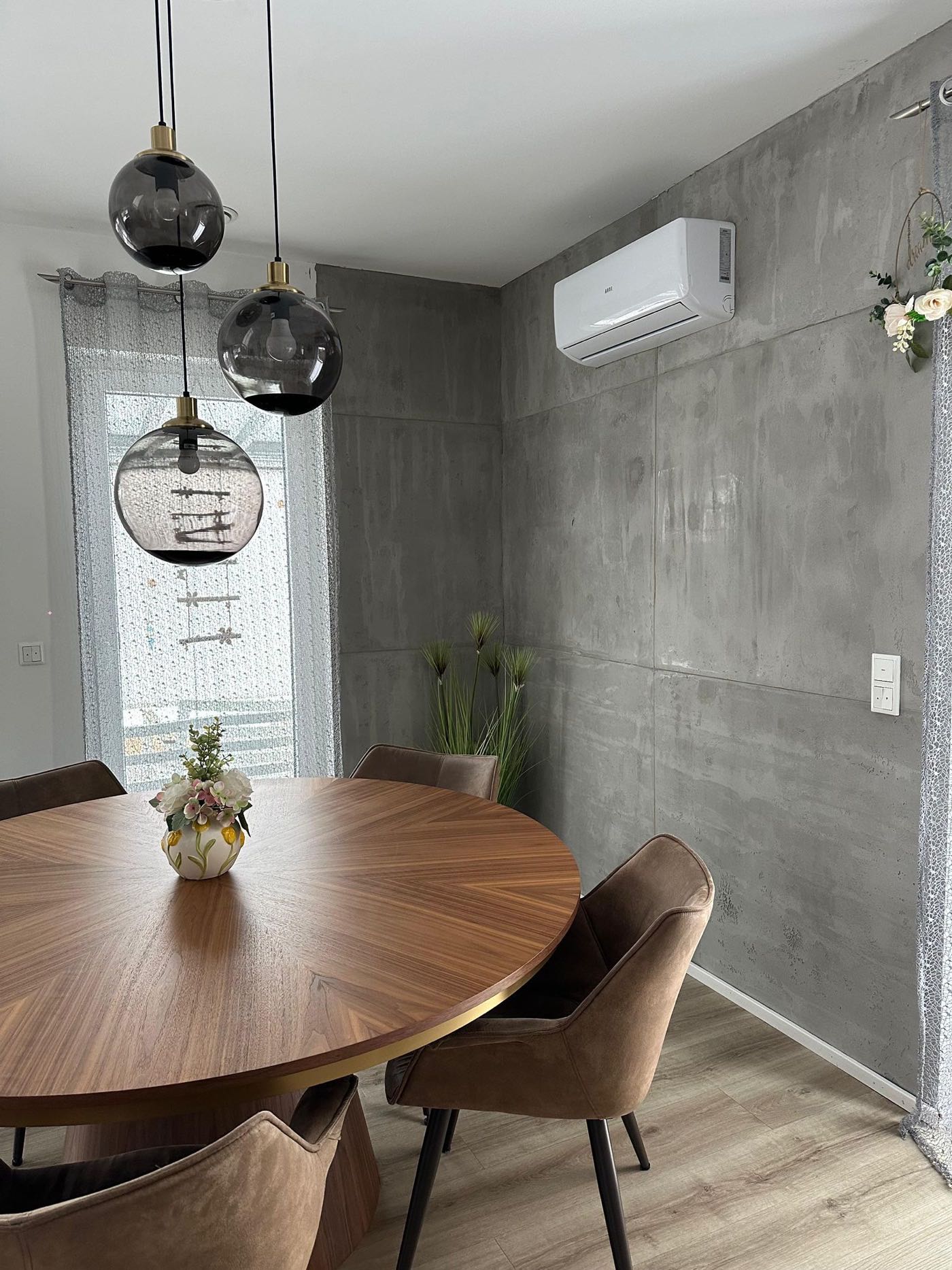 Esszimmer mit einer in Sichtbeton-Optik gespachtelten Wand hinter dem Esstisch